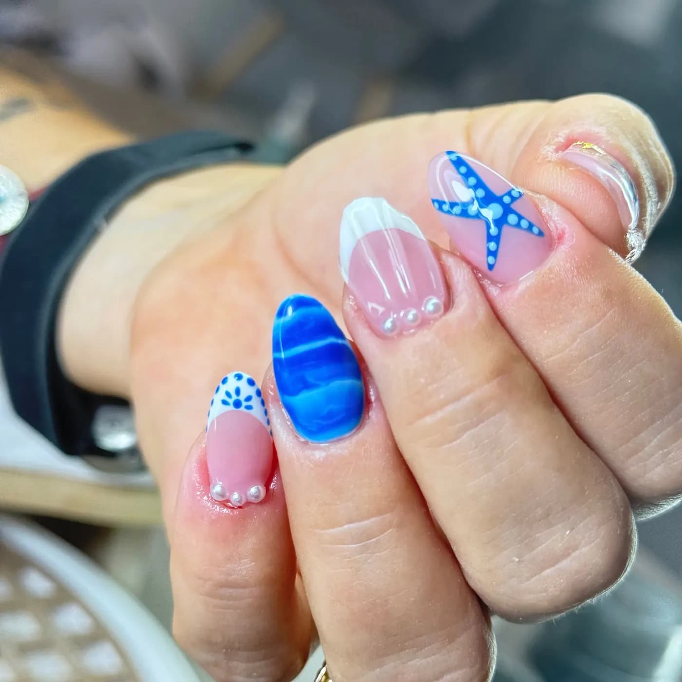 Nail art marinho: estrela-do-mar azul desenhada à mão, pérolas aplicadas e francesa branca