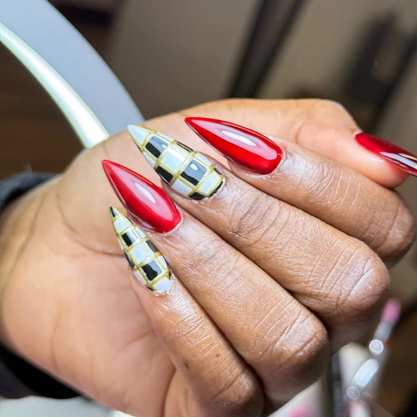 Unhas stiletto vermelhas alternadas com xadrez preto e branco