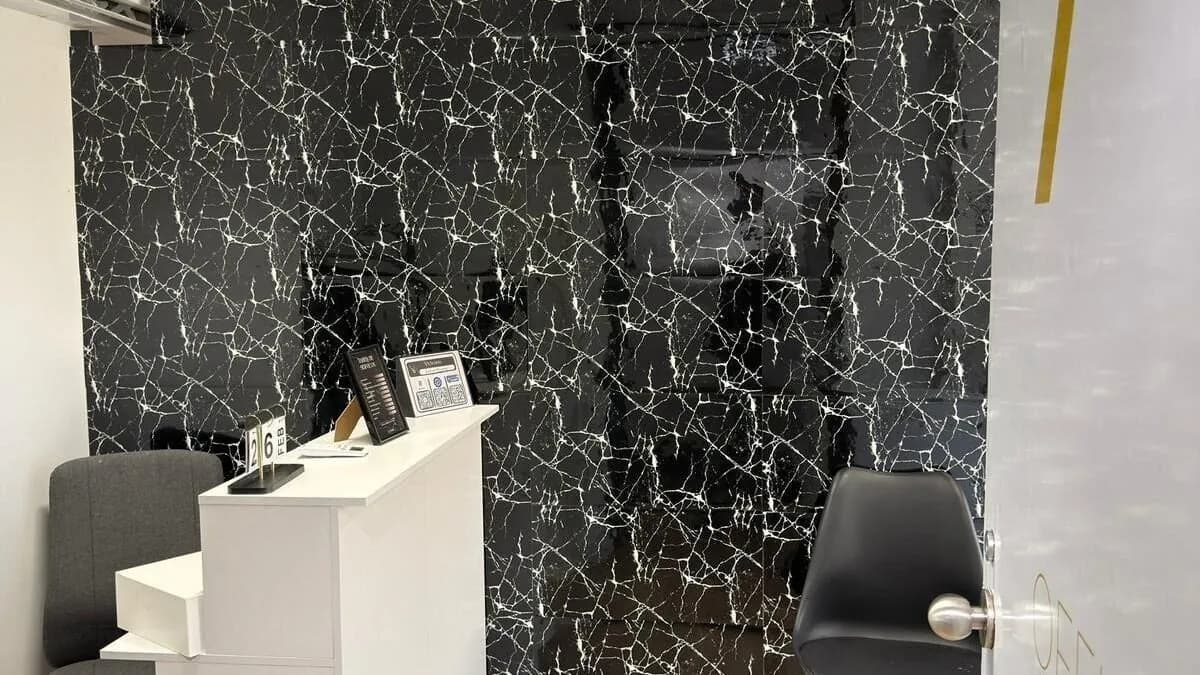 Recepção do estúdio, com parede de mármore negro e balcão branco